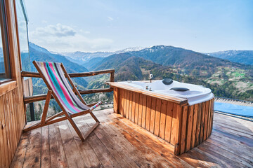 Calm relaxation place with outdoor whirlpool and deckchair with amazing mountains view