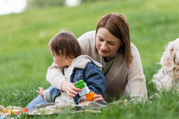 woman near colorful cubes and daughter with down syndrome in park