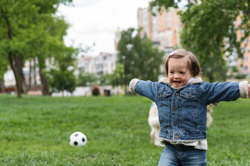 excited autistic girl running in park near blurred soccer ball