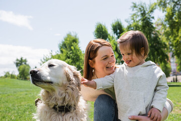 disabled kid with autism cuddling golden retriever near happy mother