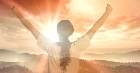 Composition of fit woman raising hands over landscape and sun