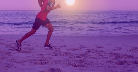 Composition of athletic man running on the beach over sea and sun