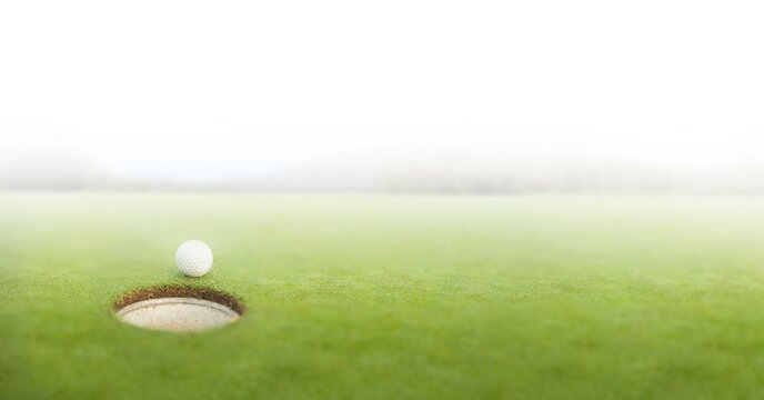 Composition of golf ball on golf course over white blur