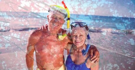 Fototapeta na wymiar Composition of senior couple wearing swimming goggles, embracing on beach and autumn foliage