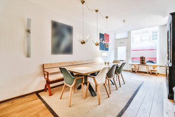 Modern design of apartment dining room with wooden table and chairs with bench under pendant lamps