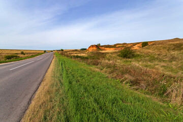 Asphalt road among hills and green grass.