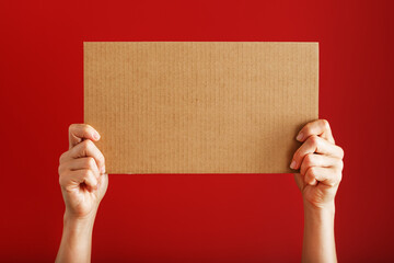 A blank sheet of cardboard in your hands on a red background.