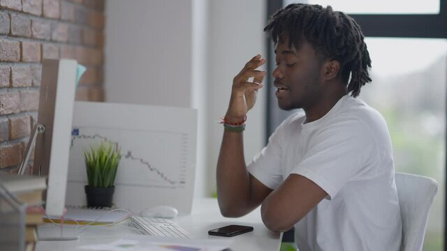 Young nervous African American man looking at computer monitor making shocked facial expression and gesturing. Middle shot side view of worried freelancer getting bad news in e-mail