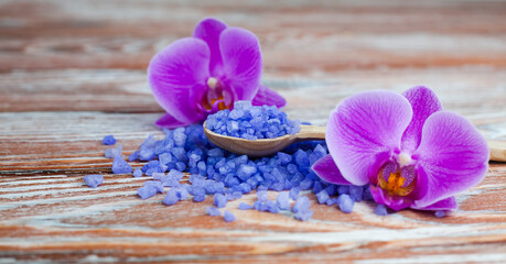 Fototapeta na wymiar Spa composition with sea salt and orchids on wooden background. Spa treatments. Close-up. Copy space.