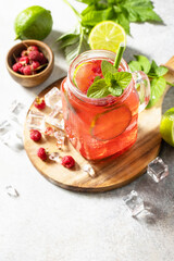 Soft drinks, healthy beverage. Refreshing summer glasses drink raspberry with mint lime and ice on a stone table. Copy space.