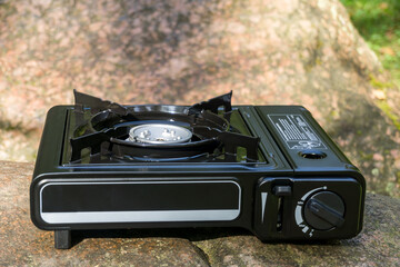 Camping gas stove on the stone. Portable equipment for cooking outdoors.