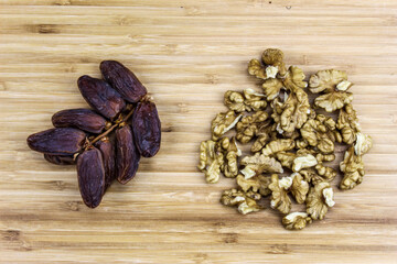 A sprig of date fruit with a walnut kernel on a wooden tray.
