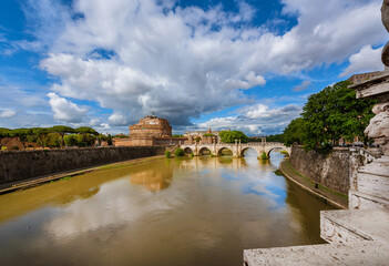 Fototapeta na wymiar View of River Tiber with the Holy Angel Castle and Bridge under a cloudy sky in Rome, from the nearby Victor Emmanuel II Bridge