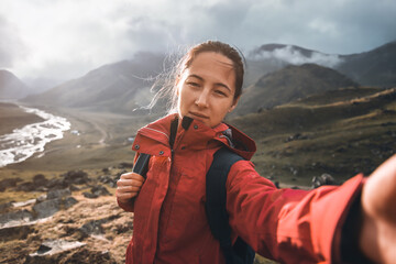 Traveler backpacker young woman taking selfie  on background of mountain in in summer outdoor.