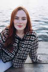 Red hair girl with freckled face outdoors near the lake. Natural beauty, eco lifestyle, nature concept