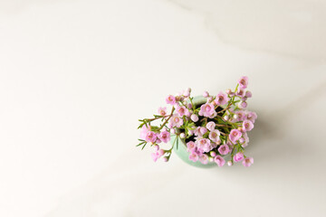 Obraz na płótnie Canvas small vase of wax flowers on a light marble table