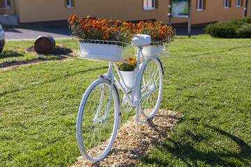 Ein Weisses Fahrrad als Blumenständer mit roten blumen