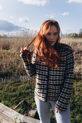 Red hair girl with freckled face outdoors near the lake. Natural beauty, eco lifestyle, nature concept