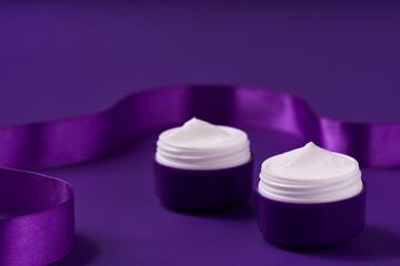 night moisturizer and silk ribbon on a purple background.
