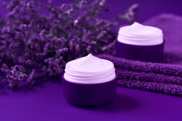 Obraz na płótnie Canvas Night moisture lotion or body cream in a purple jar on a table, copy space for text.