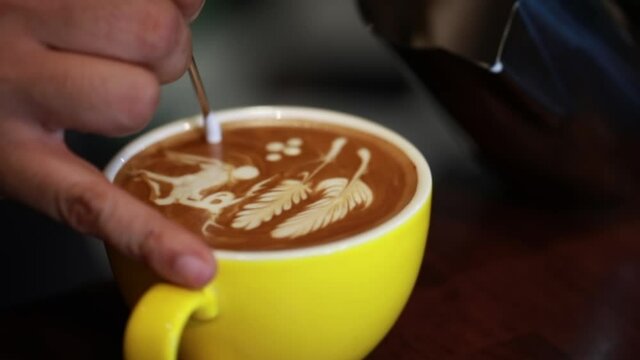 Close Up Barista pouring milk in coffee make rate art on top of hot coffee