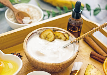 Homemade cosmetic cream with banana from natural ingredients. Banana face mask at home for wellness skin and body care. Diy natural cosmetics concept background