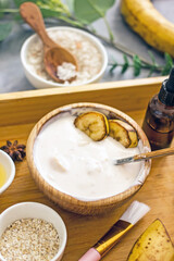 Natural ingredients for a cosmetic mask.Homemade skincare face banana mask banner. Homemade natural wellness cosmetics with banana pulp, yolk, honey, oatmeal, copy space, flat lay.