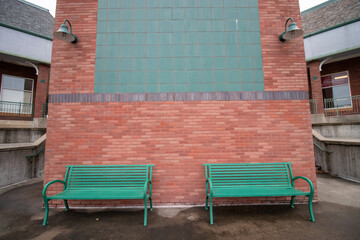 Back of brick building shopping center on cloudy day in winter with green metal park benches, super wide angle lens shot