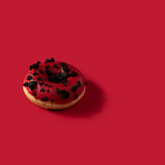 Donut with cred glazed and chocolate topping on red backgroud