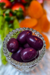 olives in a bowl and fruits in the background, cold dish, cold platter,accompaniment to wine, snack to wine