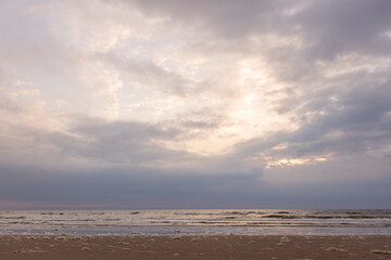 Bright sunset sky above pristine Dutch North sea beach during on overcast day. Coastal weather and climate conditions concept.