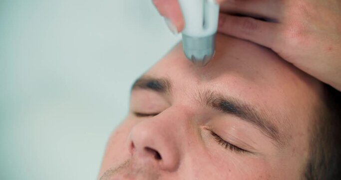 Close-up face a male client who is having a non-injection mesotherapy procedure on his forehead by using Dermadrop TDA device.