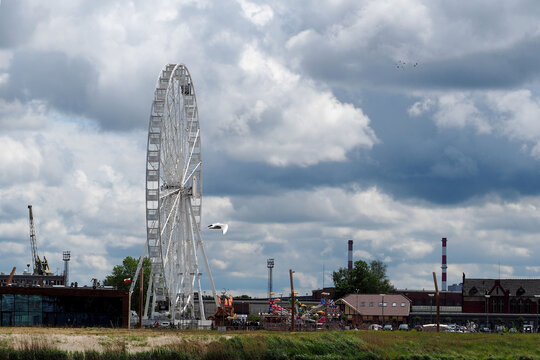 ferris wheel on the river bank against the background of blue sky with clouds side view - Powered by Adobe