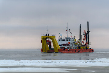 Vessel engaged in dredging at sunset time. Hopper dredger working at sea. Ship excavating material...