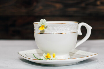 A beautiful white cup with a gold border decorated with flowers. Business account design.