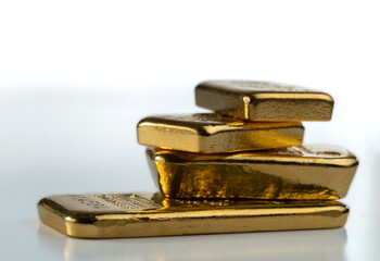 Four gold bars of various weights on a light background. Selective focus.