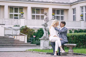 A tender beautiful newlywed couple sits on a bench against the b