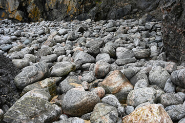 Abstract of large grey rocks at foot of black volcanic cliffs