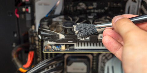 Clean your computer from dust. Cleaning a dirty computer from dust with a special brush close up. Place for your text. Banner for advertising and website header.