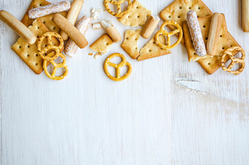 Delicious crackers and bread sticks top view on white background, flat lay. Space for text.