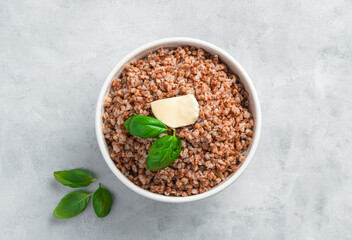 Boiled buckwheat with butter on a gray background.