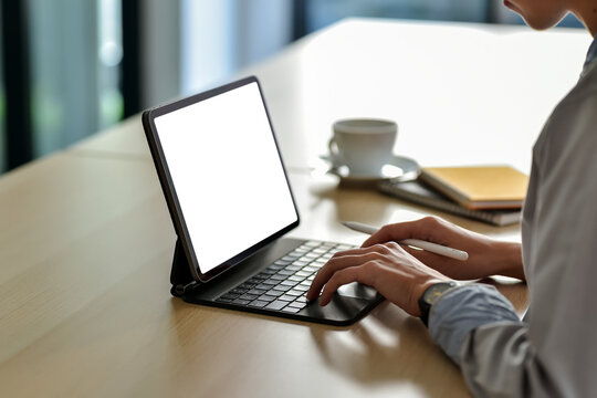 Image of a businesswoman sitting in working at the office holding a pen using tablet blank white screen. Mock up.