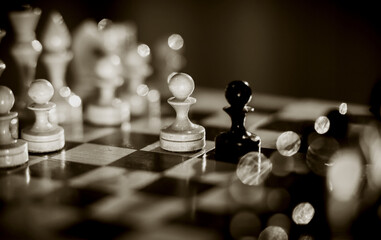 Two pawns - black and white. Wooden chess pieces on the chessboard.