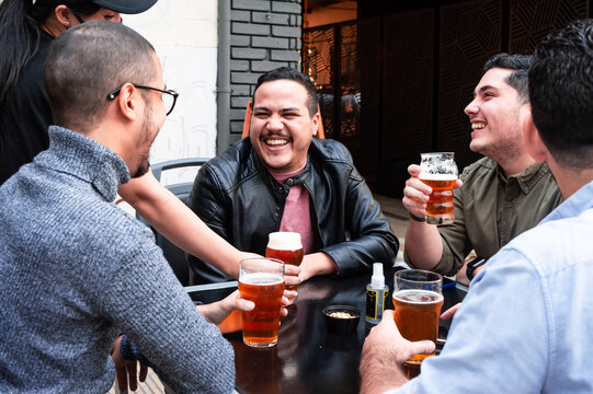 Group Of Friends Sitting Outside A Bar, While A Bartender Pours Them A Glass Of Craft Beer.