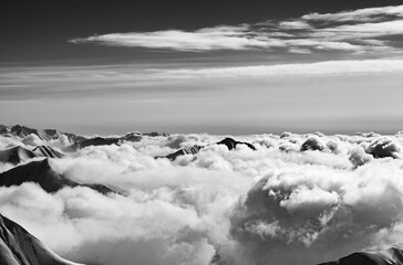 Black and white snowy mountains covered with beautiful sunlight clouds at sunny winter evening