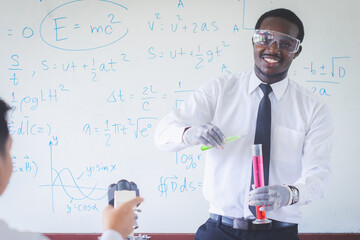 African teacher is doing science experiments inside the classroom with a scientific equations in background