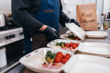 Food in disposable dishes ready for delivery. The chef prepares food in the restaurant and packs it in disposable lunch boxes.