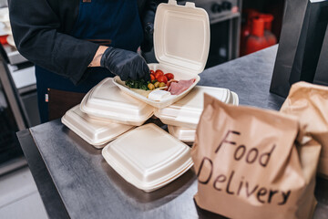 Food in disposable dishes ready for delivery. The chef prepares food in the restaurant and packs it...