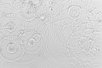 de-focused. Blurred desaturated transparent clear calm water surface texture with ripples, splashes and bubbles. Trendy abstract nature background. White-grey water waves in sunlight. Copy space.