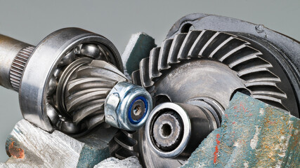 Closeup of gear wheel mechanism inside broken angle grinder machine on a gray background....